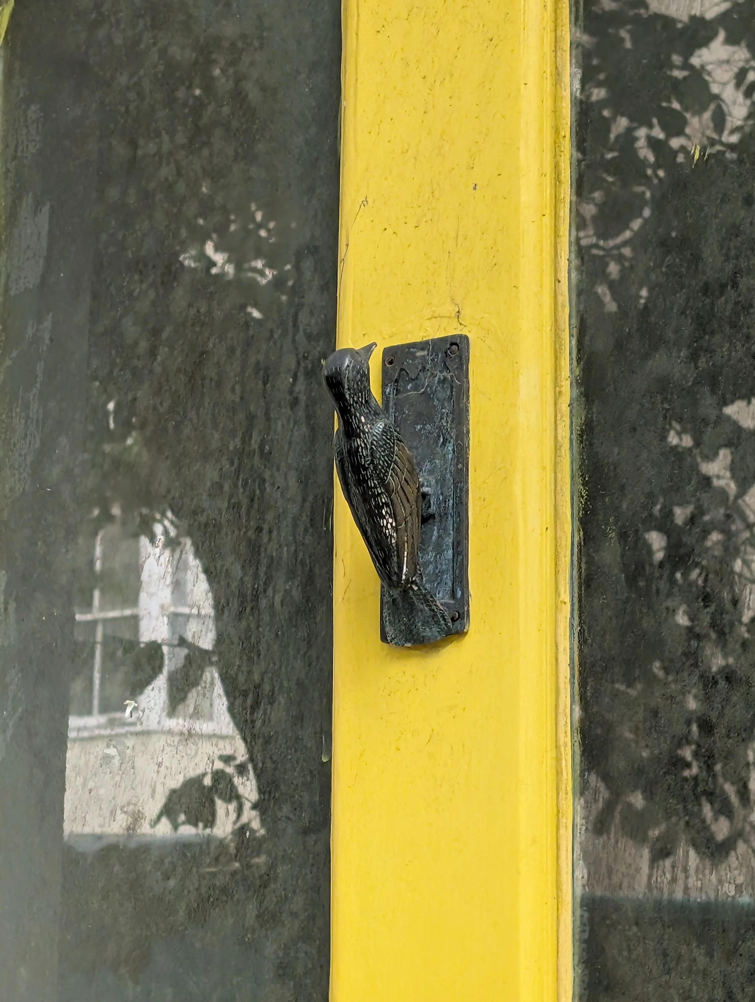 ornate bird knocker on yellow door