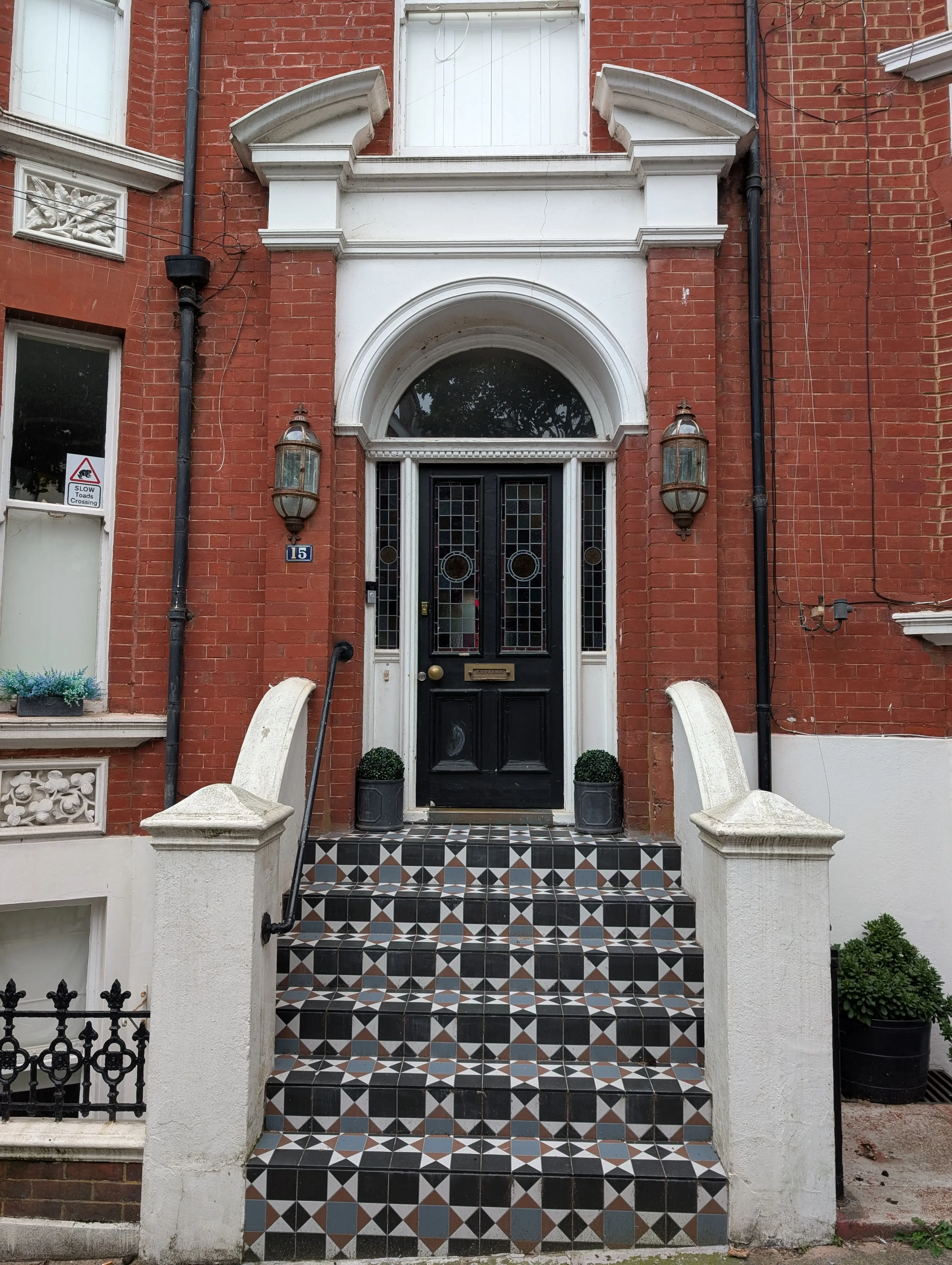 black door ornate glass and tiling separating ornate door lamps