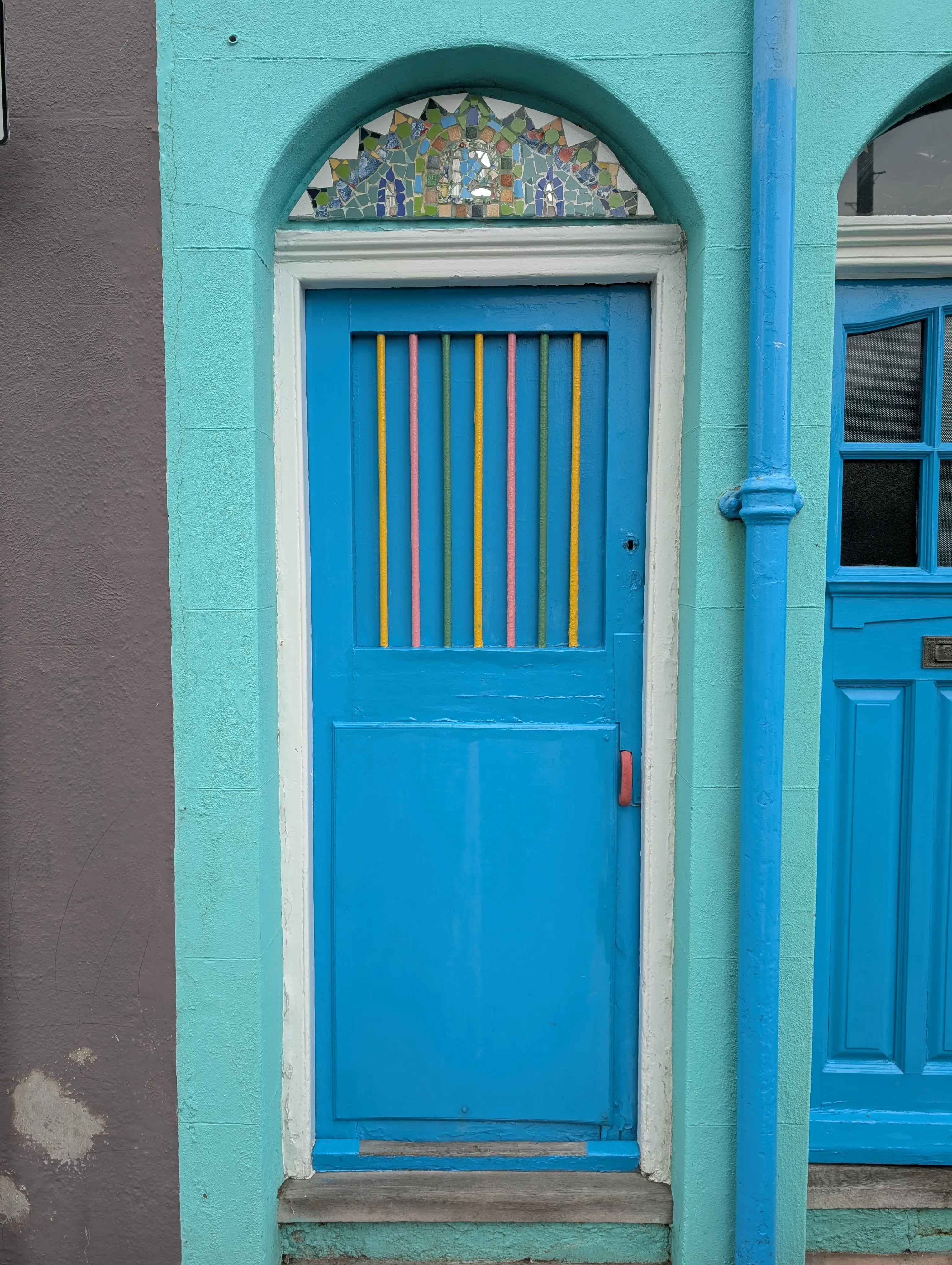 blue door with multi-colour bars and colourful glasswork