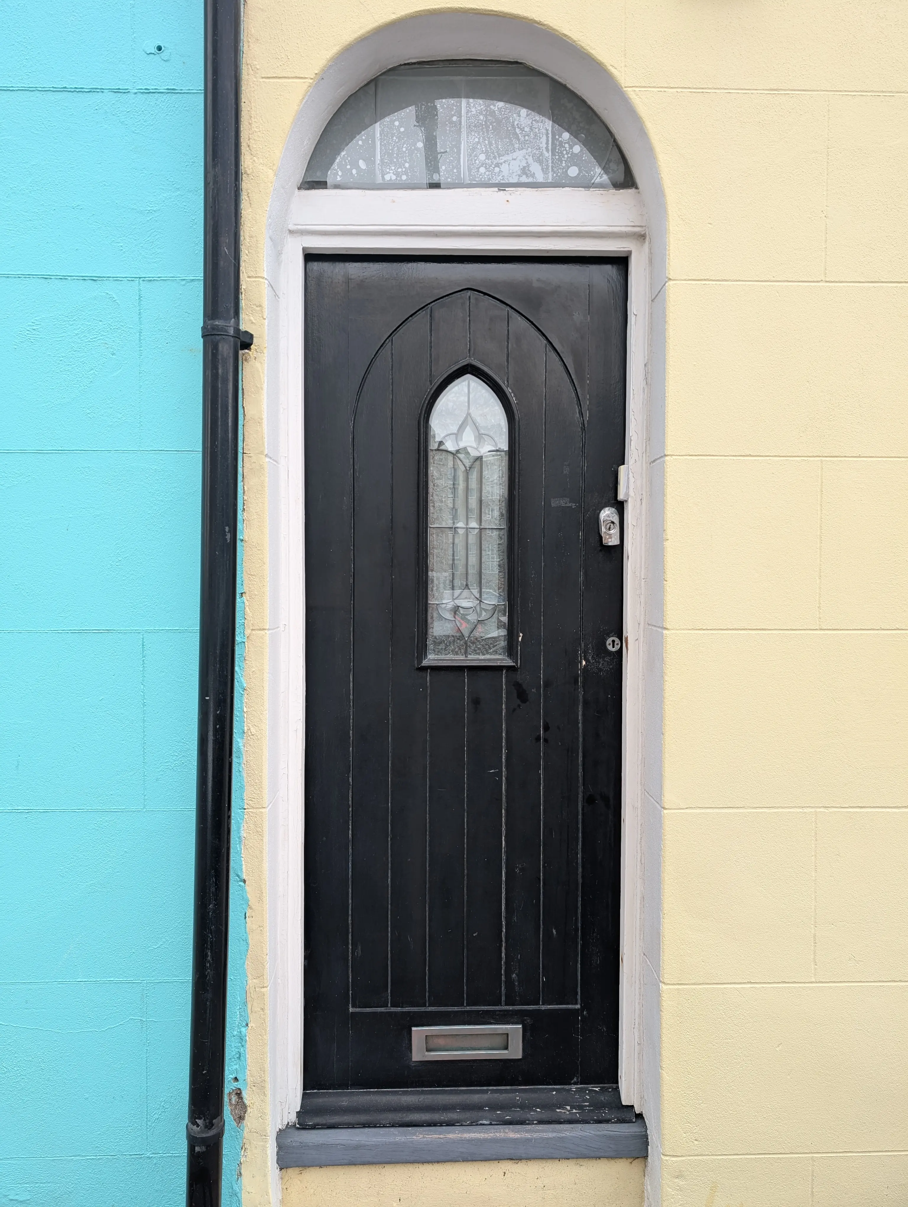 black door with church-esque window on yellow wall