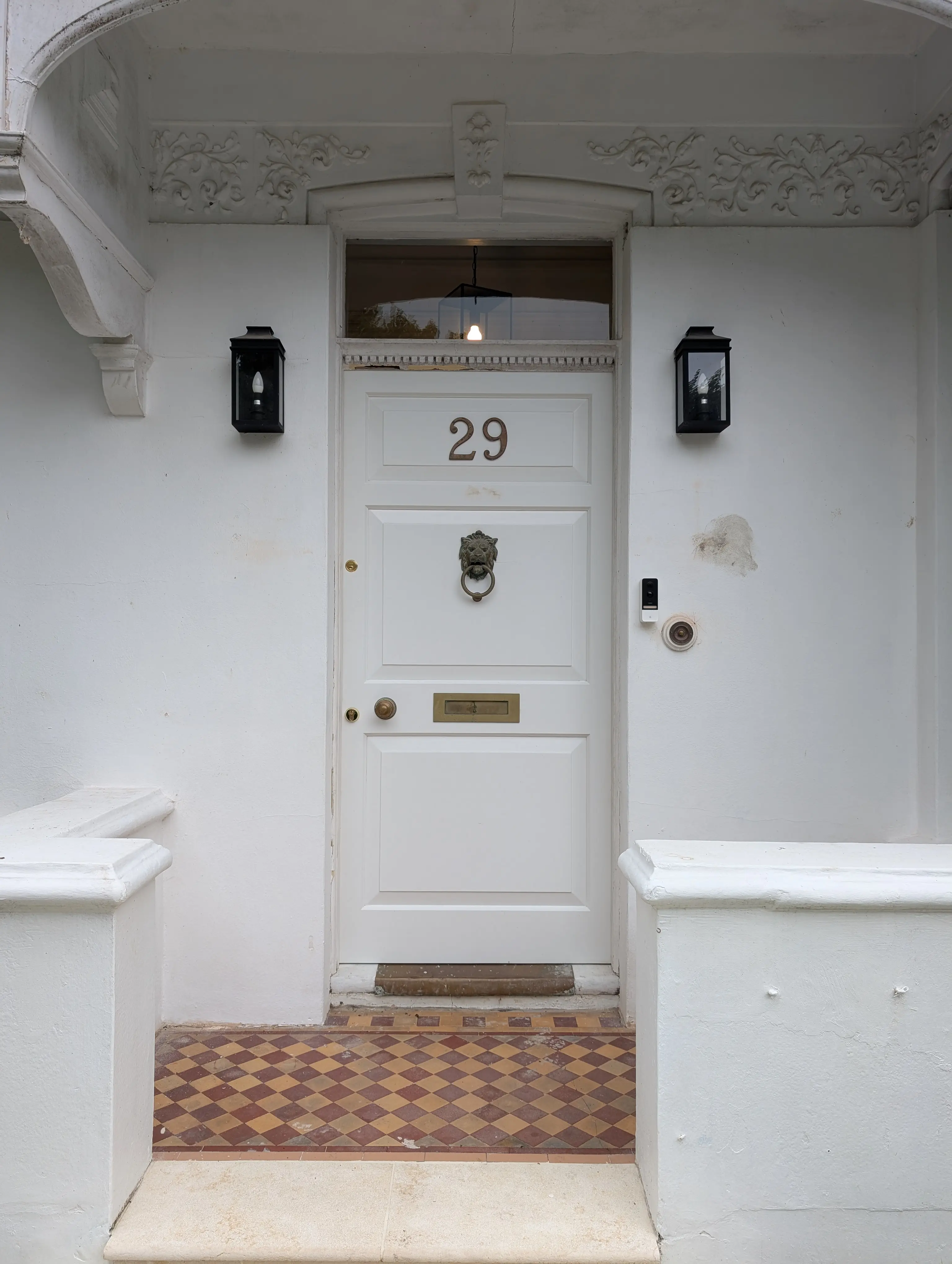 white door with lion knocker and black surrounding lamps